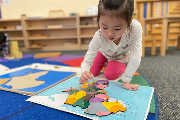 Children's House student doing a world map puzzle
